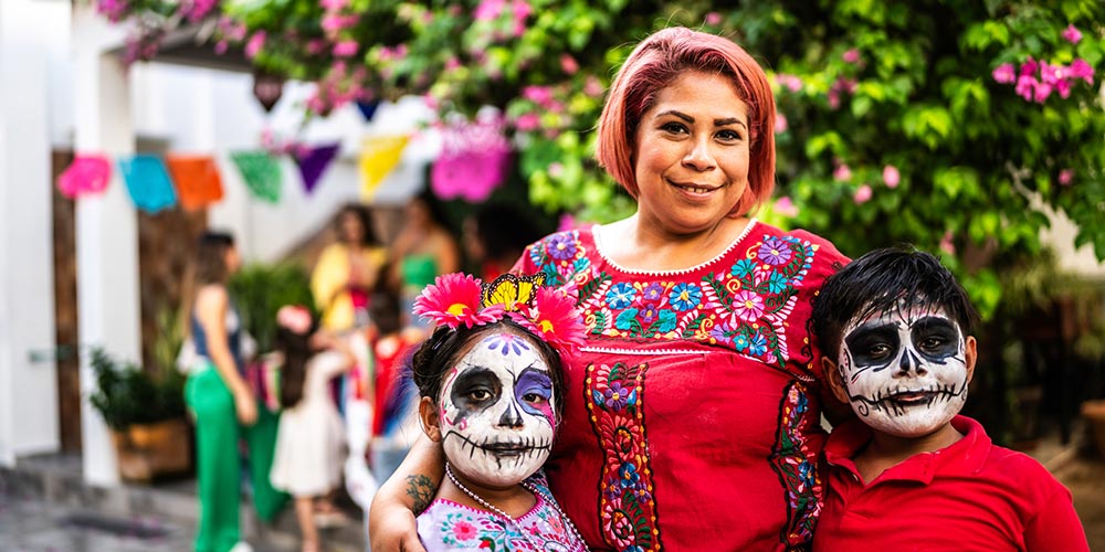 Portrait of mother and kids with sugar skull face paint during day of the dead celebration